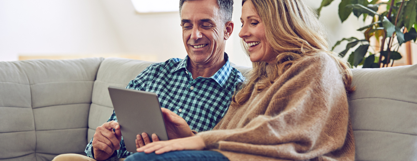 Couple sitting on a couch looking at an iPad